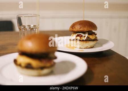 Leckere Hamburger mit Zahnstocher, während sie auf einem weißen Teller auf dem Tisch serviert werden Stockfoto