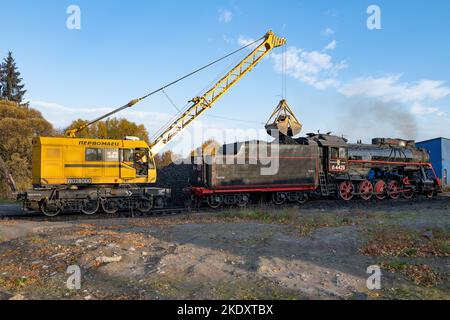 SORTAVALA, RUSSLAND - 07. OKTOBER 2021: Eisenbahnkran KZh-462 „Pervomaets“ lädt mit Kohle die alte sowjetische Dampflokomotive (L-4429, Lebedyanka) Stockfoto