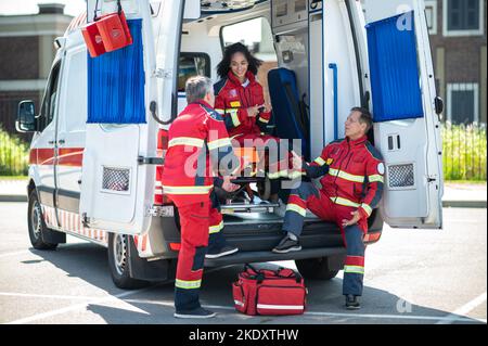 Team von EMS-Mitarbeitern, die vor ihrer Schicht etwas diskutieren Stockfoto