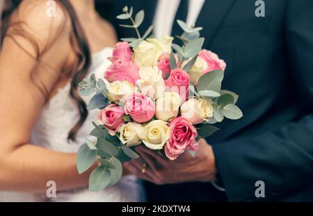 Blumen, Hochzeit und Liebe mit einem Blumenstrauß in den Händen einer Braut und eines Bräutigams am Hochzeitstag Nahaufnahme. Rose, verheiratet und Feier Veranstaltung mit einem Stockfoto