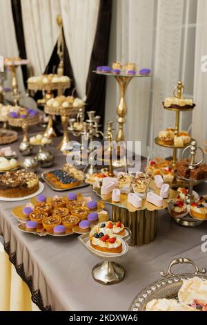 Tisch mit Kuchen, Süßigkeiten, Süßigkeiten, Buffet. Desserttisch für eine Party-Leckereien für den Hochzeitsbankett-Bereich. Süßigkeitenbar aus nächster Nähe. Stockfoto