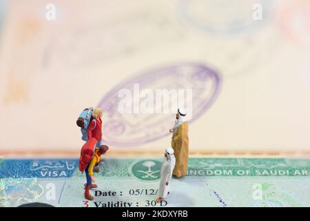 Miniaturspielzeugkonzept von zwei Arabern, die ausländische Gäste mit Saudi-Arabien-Visum als Hintergrund begrüßen. Stockfoto
