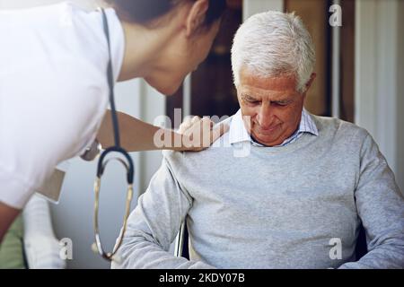 Sie sorgt für das Wohlergehen der Patienten. Eine Pflegekraft tröstet einen depressierten älteren Mann. Stockfoto
