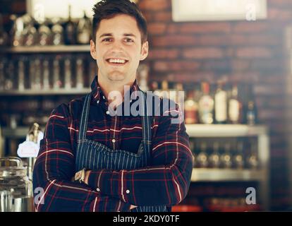 HES der stolze Besitzer eines neuen Restaurants. Porträt eines lächelnden jungen Unternehmers, der in einem kleinen Restaurant steht. Stockfoto