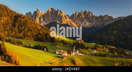 Ein Panoramabild aus dem Jahr 2:1 von einem herbstlichen Sonnenuntergang an der berühmten Kirche und dem Dorf Santa Maddalena vor dem Geisler- oder Geisler-Dolomiten-Gipfel Stockfoto