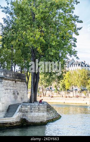 Paris, Frankreich - 09-12-2018: Sitzendes Mädchen studiert am Ufer der seine in Paris Stockfoto