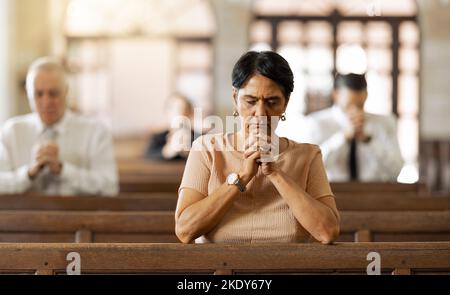 Glaube, Frau und Beten in Kirche, Religion und spirituellem verbinden, kommunizieren oder glauben. Ältere Frau, reife Dame oder Gebet in der Kapelle mit Stockfoto