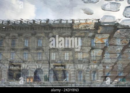 Der Königspalast von Stockholm in Reflexion von der Kopfsteinpflasterpfütze Straße. Stockfoto