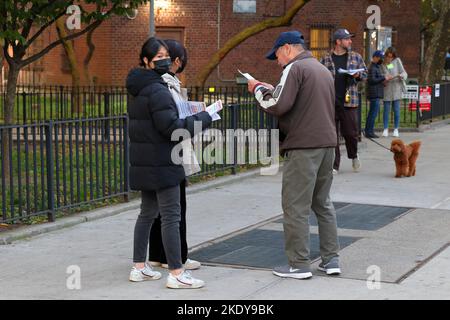 Zwei Chinesisch-amerikanische Frauen mit mehrsprachigen Begleitblättern, die vor einem Wahllokal in Manhattan Chinatown, New York, am 8. November 2022 Wahlkampf veranstalteten Stockfoto