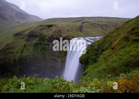 Der Zeitrafferblick auf einen Wasserfall, der an einem bewölkten Tag in den Bergen fließt Stockfoto