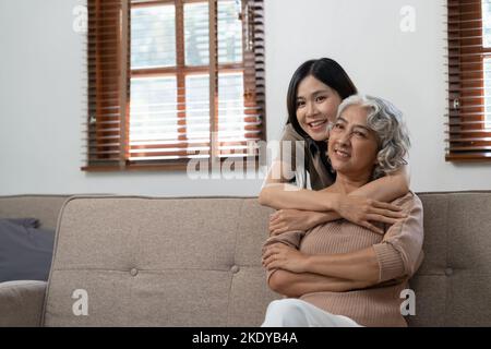 Lächelnd Erwachsene Tochter umarmt ältere Mutter. Zwei Generationen Konzept, schöne junge Frau umarmt reife Frau, posiert für Foto zusammen. Stockfoto