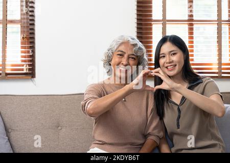 Lächelnd Erwachsene Tochter umarmt ältere Mutter. Zwei Generationen Konzept, schöne junge Frau umarmt reife Frau, posiert für Foto zusammen. Stockfoto