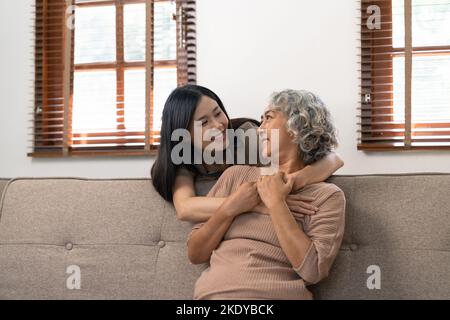 Lächelnd Erwachsene Tochter umarmt ältere Mutter. Zwei Generationen Konzept, schöne junge Frau umarmt reife Frau, posiert für Foto zusammen. Stockfoto