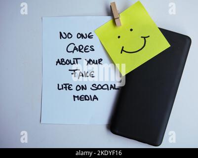 Eine Nahaufnahme einer Notiz mit einem lustigen Social-Media-Beitrag in der Nähe einer Haftnotiz mit einem Smiley-Gesicht Stockfoto