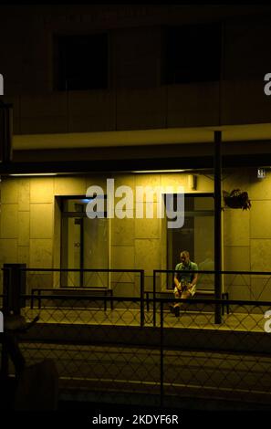 Eine vertikale Aufnahme eines einsamen Mannes, der am Abend in Keszthely an einer Station auf den Zug wartet Stockfoto