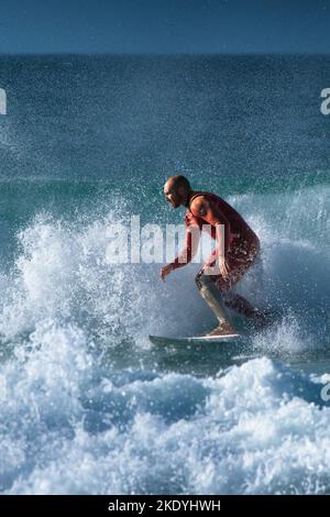 Spektakuläre Surfaktion als männlicher Surfer reitet auf einer Welle im Fistral in Newquay in Cornwall in England in Großbritannien. Stockfoto