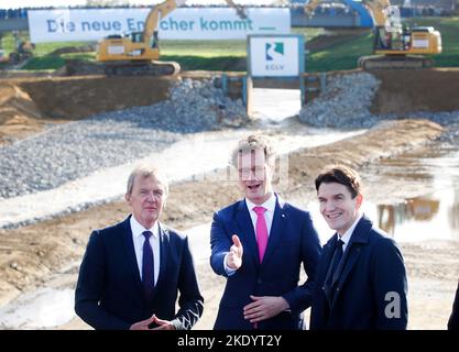 09. November 2022, Nordrhein-Westfalen, Voerde: Nordrhein-Westfalens Ministerpräsident Hendrik Wüst (CDU), Emanuel Grün (l), Technischer Direktor der Emschergenossenschaft, und Uli Paetzel (r), Vorsitzender der Emschergenossenschaft, weihen die neue Mündung der Emscher in den Rhein ein. Bisher stürzte das Emscherwasser an einer Mündungsstruktur in Dinslaken bis in eine Tiefe von rund fünf Metern in den Rhein. Dies verhinderte, dass Fische stromaufwärts schwimmen konnten. Mit der Renaturierung der Emscher wird der Höhenunterschied in einer Auenlandschaft nun sanft ausgeglichen, und die Mündung ist m Stockfoto
