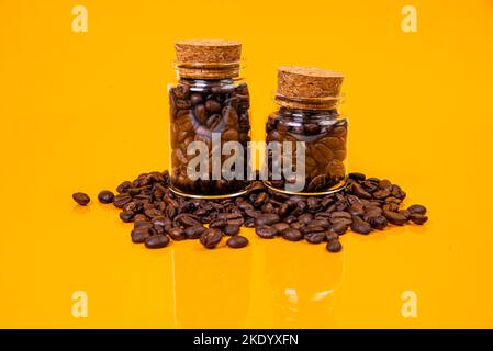 Fiel viele geröstete Kaffeebohnen in ein Glas, in Eimer-Glas. Selbstschneidende Schraube für Metall, für Eisen, verchromt selbstschneidende Schraube, isoliert auf ora Stockfoto