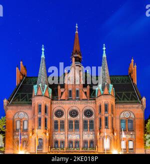 Das beleuchtete alte Rathaus von Neumünster vor einem dunkelblauen Nachthimmel Stockfoto