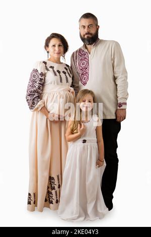 Ukrainische Familie von Schwangeren, Vater und Tochter in traditionellen Volkskleidung isoliert auf weißem Hintergrund Stockfoto