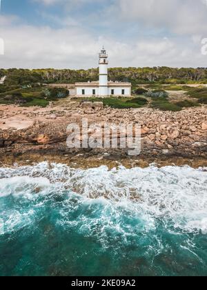 Der Leuchtturm an einem felsigen Ufer vom Cap de ses Salines in Spanien Stockfoto