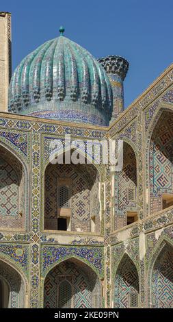 Eckansicht mit Kuppel und Bögen im Innenhof des Ulugh Beg madrassa auf dem Registan-Platz im UNESCO-Weltkulturerbe Samarkand, Usbekistan Stockfoto