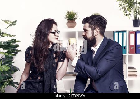 Mittagessen im Büro. Zwei Kollegen entspannen sich in der Mittagspause. Teilen Sie das Mittagessen mit einem Kollegen. Flirten mit Kollegen. Bärtiger Mann und attraktive Frau. Mann und Stockfoto