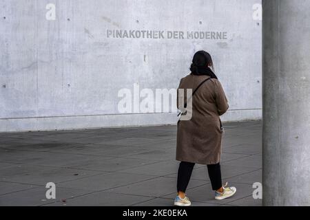 Eine Frau geht vor das Museum Pinakothek der Moderne in München. Pinakothek der Moderne. Architekt Stephan Braunfels. Stockfoto