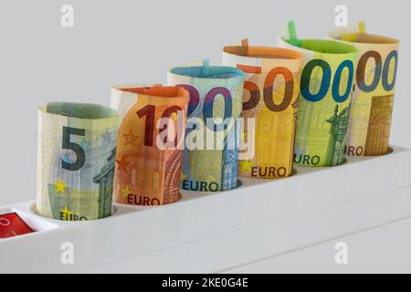 Symbolbild der Stromkosten: Euro-Banknoten in einer Mehrfachsteckdose Stockfoto