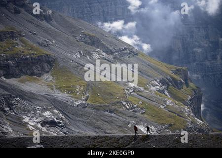 Kleine Silhouetten von zwei Personen, die einen Berg mit einer schönen Landschaft im Hintergrund wandern Stockfoto