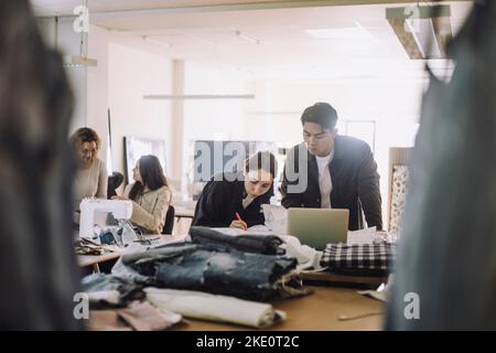 Multirassische Designer und Designer, die in der Werkstatt an einem Laptop arbeiten Stockfoto