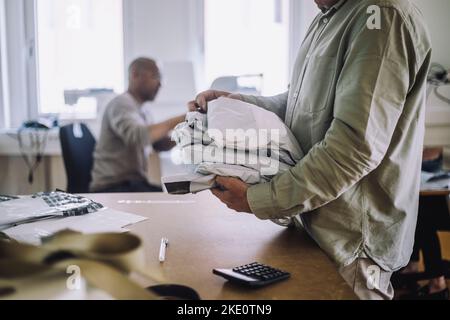 Mittelteil der männlichen Design professionelle halten Pakete in der Werkstatt Stockfoto