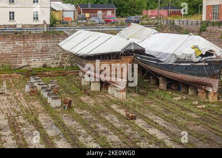 Helsinki, Finnland - 19. Juli 2022: Festung Suomenlinna. Detail der historischen Werft Viaporin Trockendock mit 2 alten abgenutzten Bootsrümpfen auf Blöcken von bedeckt Stockfoto