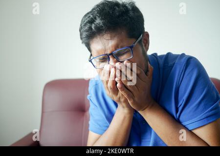 Reifer Mann hustet auf Sofa sitzen Stockfoto