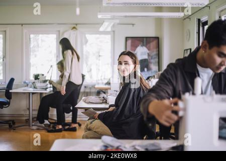Porträt einer lächelnden Modedesignerin, die in einem Workshop sitzt Stockfoto