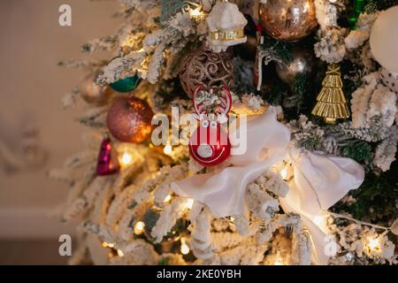 Weißer Weihnachtsbaum mit Vintage-Spielzeug, Kugeln, Girlanden auf Fichtenzweigen mit Kunstschnee, Kopierraum. Stockfoto