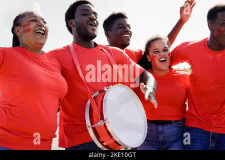 African Red Sport Fußball-Fans feiern Mannschaftssieg im Meisterschaftsspiel im Stadion - Fußball-Fans Spaß in der Menge - Fokus auf linken Mann f Stockfoto