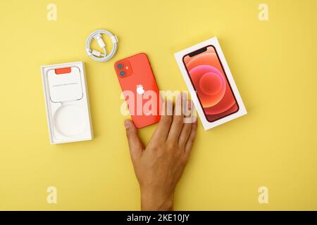 Tjumen, Russland-18. Juli 2022: IPhone 12 mini Produkt rot mit Einzelhandelsverpackung. Draufsicht, gelber Hintergrund Stockfoto