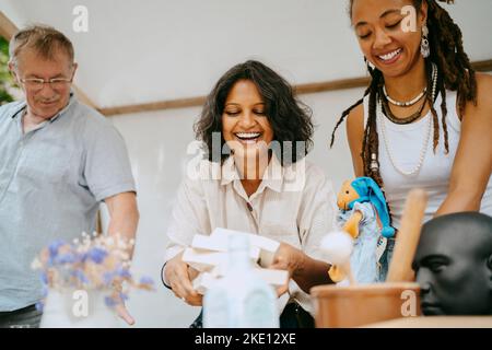 Glückliche Frau, die Bücher von Partnern in einem Stand auf dem Flohmarkt hält Stockfoto