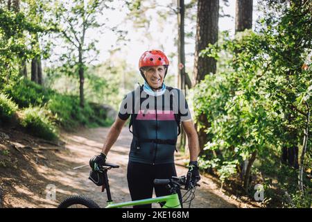 Porträt eines Mannes in Schutzkleidung, der mit dem Fahrrad auf dem Fußweg steht Stockfoto