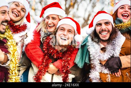 Trendige Freunde, die im Winter unterwegs sind, ziehen auf dem Sparschwein herum - Weihnachtsferien Lifestyle-Konzept mit fröhlichen Jungs und Mädchen, die Weihnachten haben Stockfoto