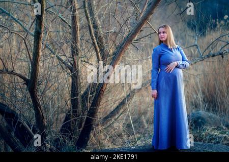 Schwanger Mädchen in einem blauen Kleid schaut in die Ferne Stockfoto