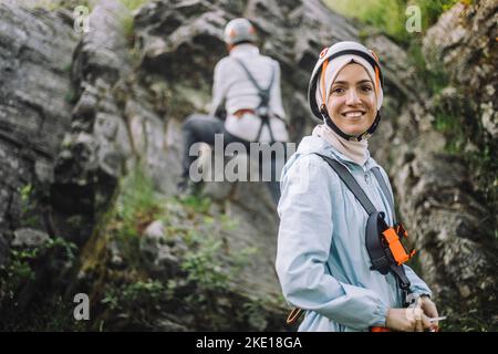 Porträt einer lächelnden Frau, die beim Klettern einen Helm trägt Stockfoto