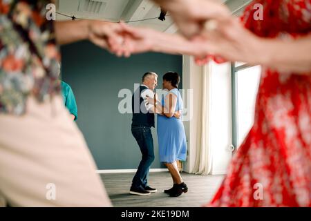 Die gesamte Länge des mehrrassischen Seniorenpaares, das im Unterricht Tanz praktiziert Stockfoto