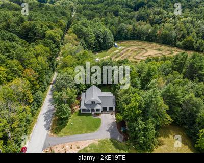 Eine Luftaufnahme eines Waldes mit einem modernen Custom New England Kolonialhaus Stockfoto