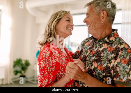 Glückliches Seniorenpaar, das sich ansieht, während es im Unterricht tanzt Stockfoto