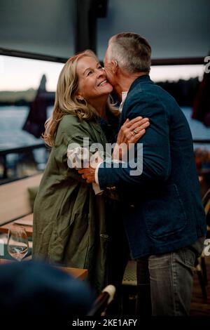 Lächelnde ältere blonde Frau umarmt Mann im Restaurant Stockfoto