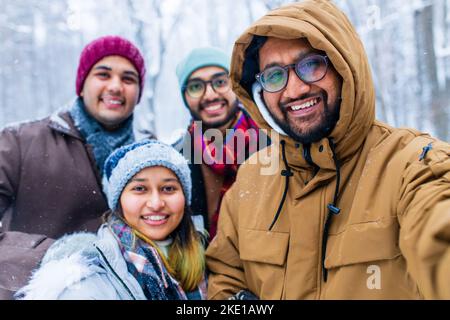 Vier Personen, die an den Feiertagen im Freien Selfie machen Stockfoto