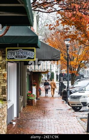 Frauen, die an einem nebligen Herbstmorgen in den Bergen einen gemauerten Bürgersteig auf der Main Street in Highlands, North Carolina, hinuntergehen. (USA) Stockfoto