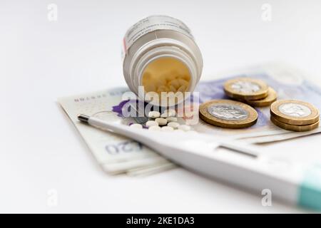 Ein Kostenkonzept für das Gesundheitswesen mit einer Flasche Medizin, einem Thermometer und Münzen auf Banknoten, die auf weißem Hintergrund isoliert sind. Stockfoto
